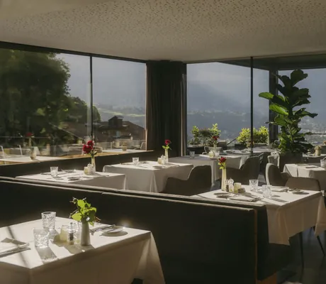 gedeckte Tische im Restaurant des Avidea mit Panoramablick auf Meran