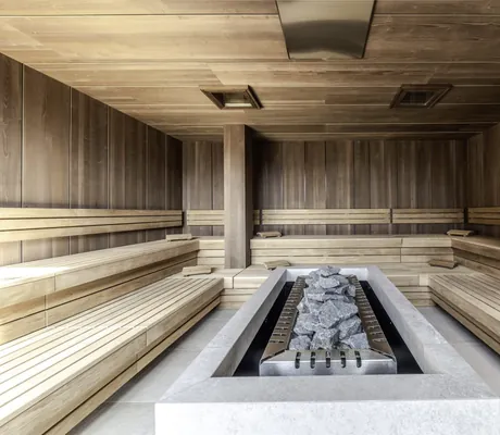 große Sauna mit langem Kohleofen in der Mitte im Avidea