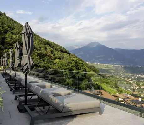 Sonnenloegen mit geschlossenen grauen Sonnenschirmen auf der Terrasse des Avidea mit Blick auf Meran