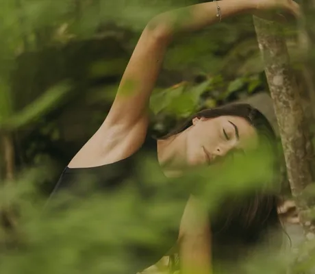 dunkelhaarige Frau in schwarzem Top macht Yoag mitten im Wald rund um das Avidea