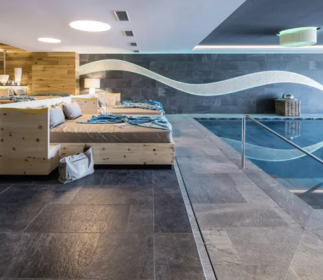 Ruheliegen am Indoorpool des Das Gerstl Alpine Retreat mit wellenförmiger Wanddekoration