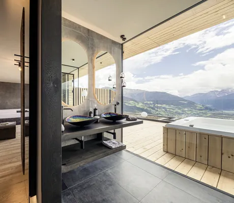 Suite mit Whirlpool auf dem Balkon und Badezimmer mit geschwungenen Waschbecken im Das Gerstl Alpine Retreat