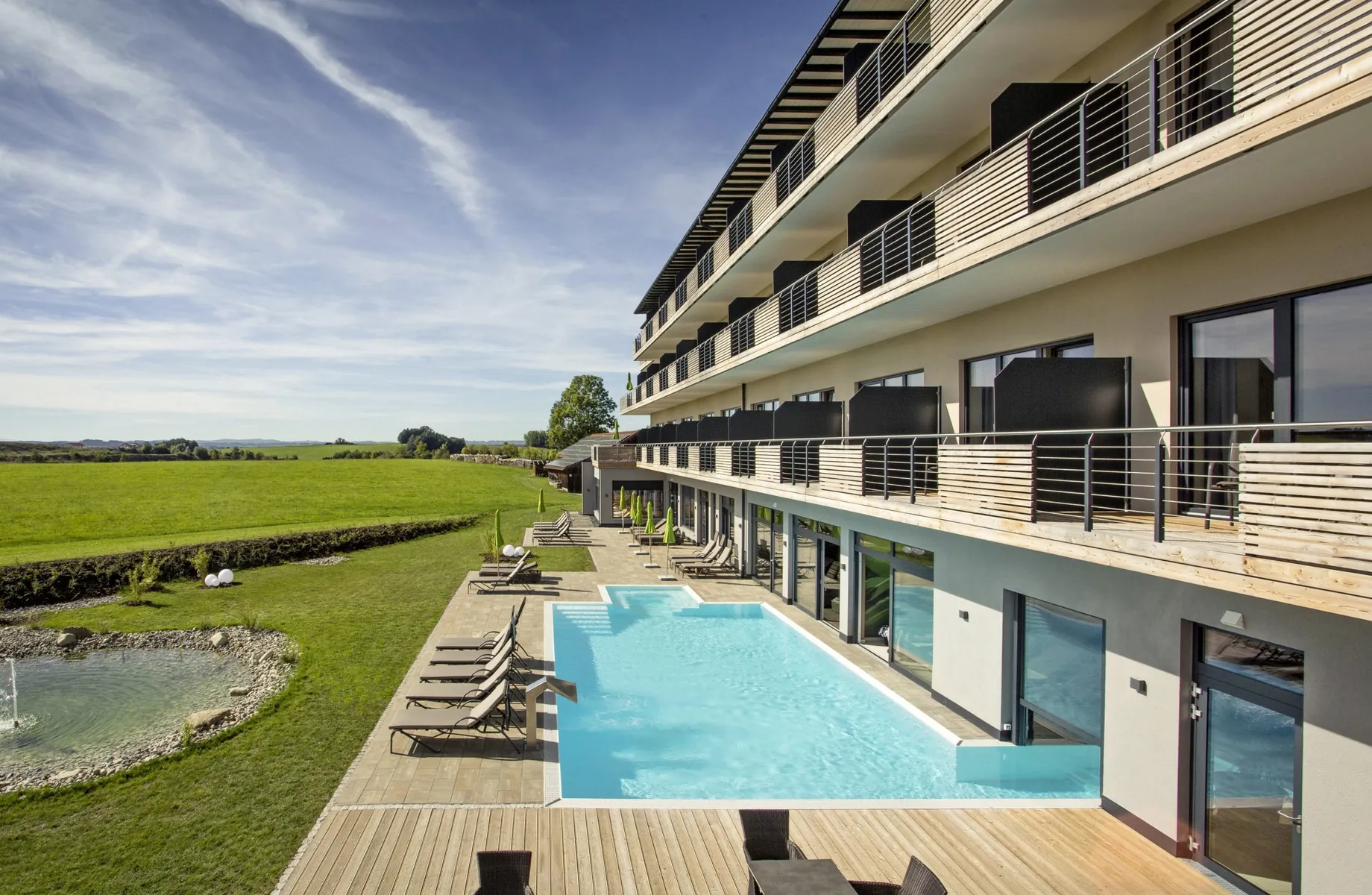 Outdoorpool mit Blick über die Wiesen vor der Fassade des Das Weitblick Allgäu