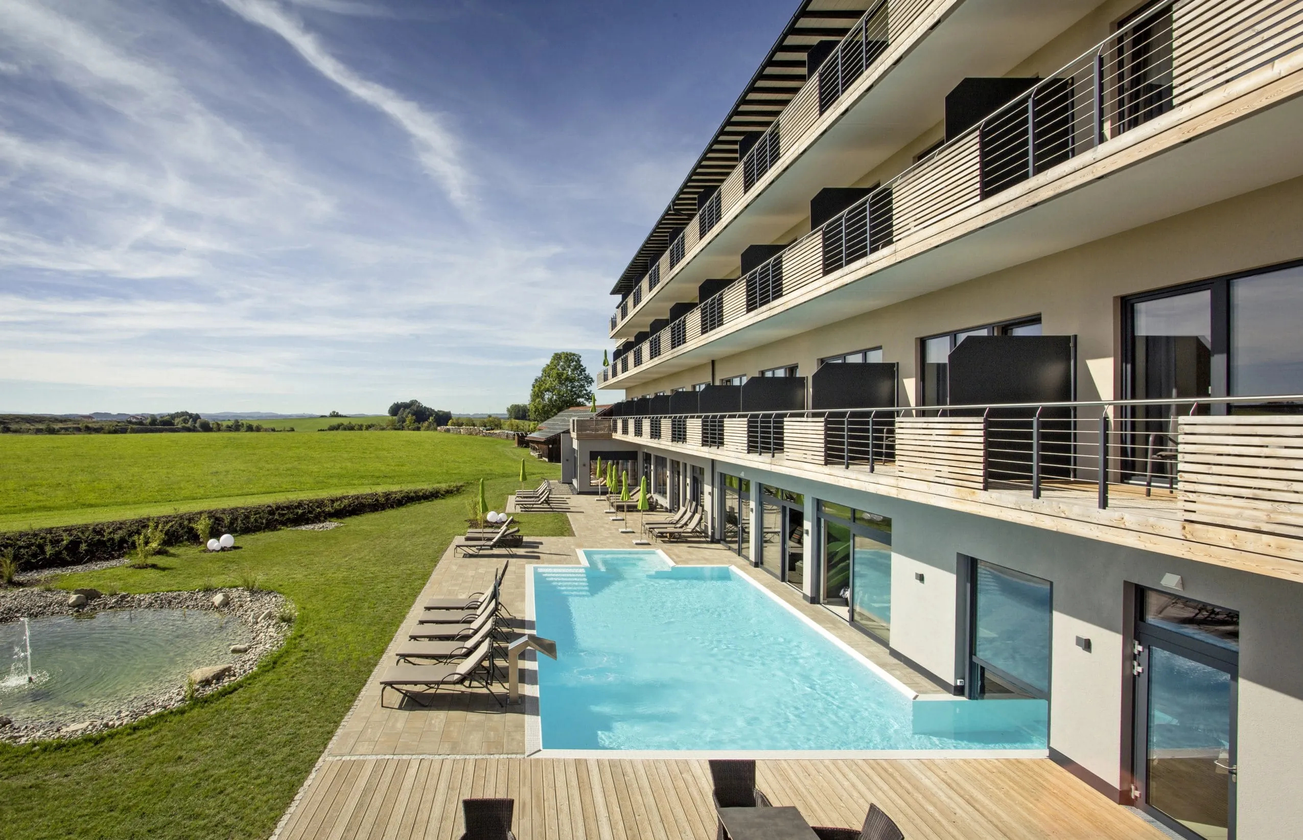 Outdoorpool mit Blick über die Wiesen vor der Fassade des Das Weitblick Allgäu