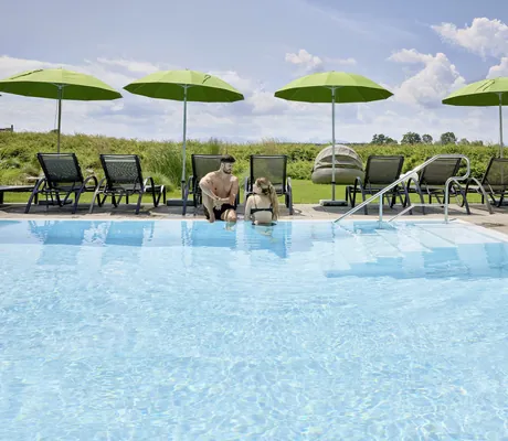 Paar unterhält sich am Beckenrand des Outdoorpools des Das Weitblick Allgäu