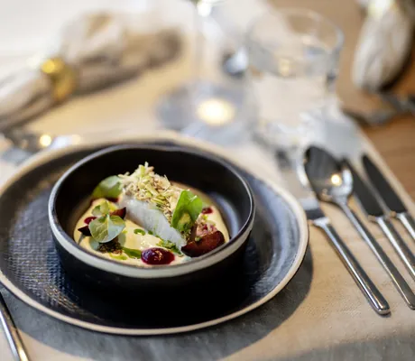 Fischgericht in dunklem tiefem Teller garniert mit Mandeln im Das.Goldberg