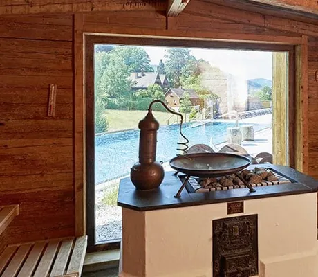 Saunaofen in der Sauna mit Blick auf den Outdoorpool des Heselbacher Hof