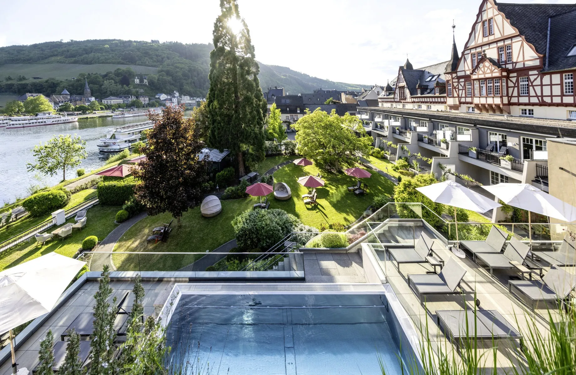 Fassade und Outdoorpool des Moselschlösschen Spa & Resort mit Blick auf die Mosel