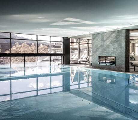 Indoorpool mit Granitwand und Blick auf blühende Bäume im Moselschlösschen Spa & Resort