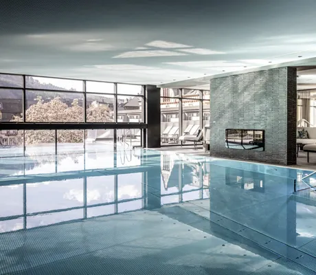 Indoorpool mit Granitwand und Blick auf blühende Bäume im Moselschlösschen Spa & Resort