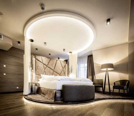 rundes Bett mit runder Lichtinstallation an der Decke in der Suite des Moselschlösschen Spa & Resort