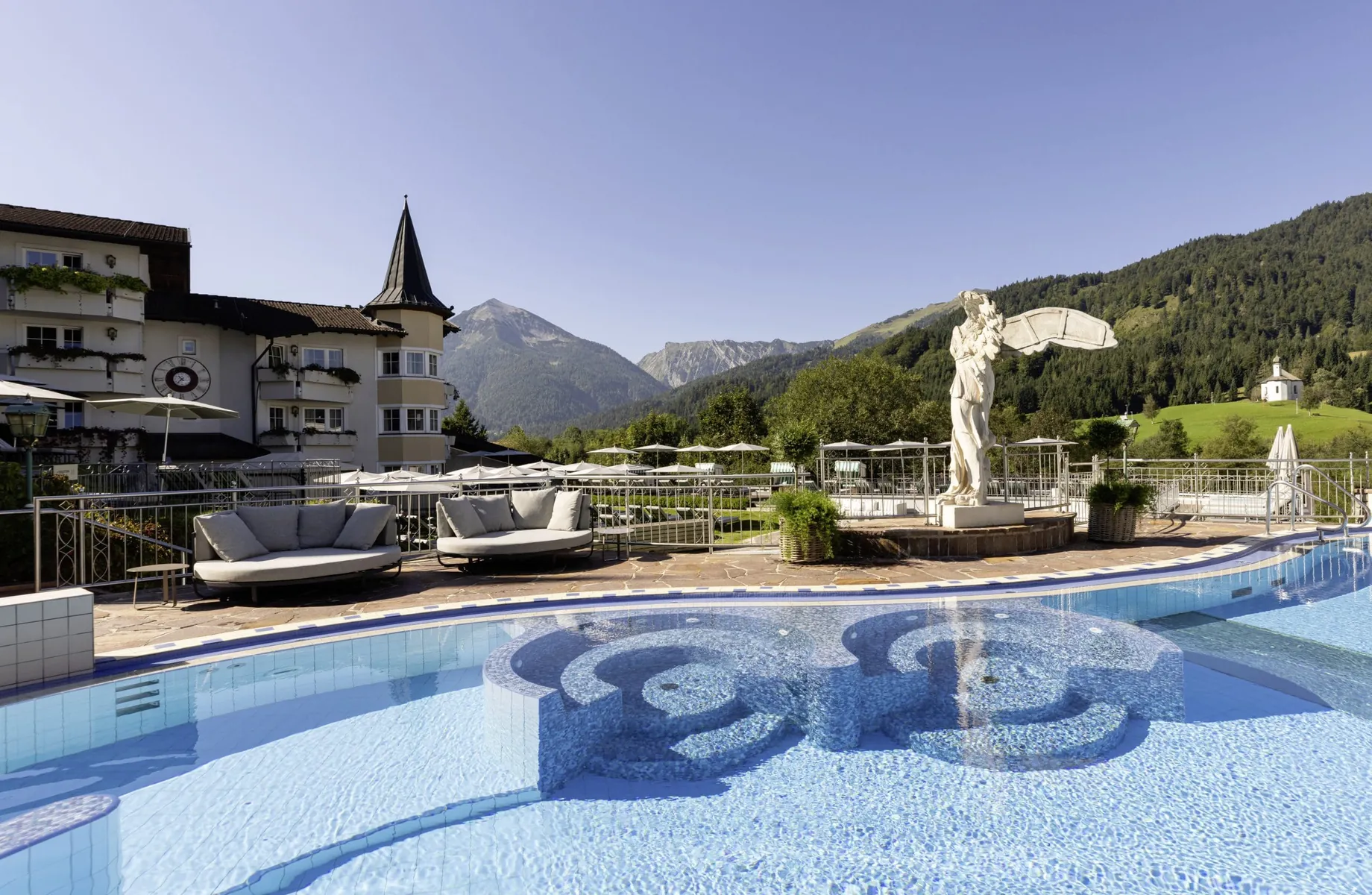 Outdoorpool im Posthotel Achenkirch mit Engel am Beckenrand und Whirlecken im Wasser