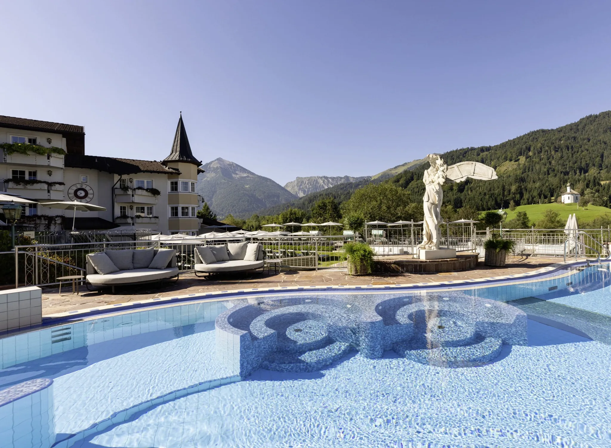 Outdoorpool im Posthotel Achenkirch mit Engel am Beckenrand und Whirlecken im Wasser