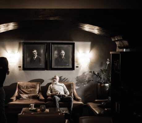 Paar in rustikaler Stube mit Ledersofa und alten schwarz/weiß-Fotografien im Romantik Hotel Stafler