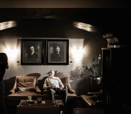Paar in rustikaler Stube mit Ledersofa und alten schwarz/weiß-Fotografien im Romantik Hotel Stafler