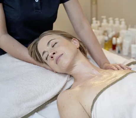 Frau in beigem Handtuch erhält Anwenung von Therapeutin im Romantischer Winkel