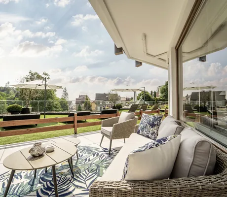 Korbmöbel auf Teppich mit Blattmuster auf der Terrasse des Romantischer Winkel