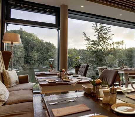 eingedeckte Tische mit pastellfarbenen Polstersesseln im Restaurant des Romantischer Winkel mit Blick in den Park