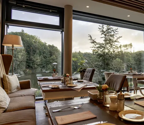 eingedeckte Tische mit pastellfarbenen Polstersesseln im Restaurant des Romantischer Winkel mit Blick in den Park