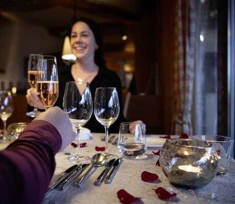 Paar an Restauranttisch im Salzano mit Rosenblättern prostet sich mit Sekt zu