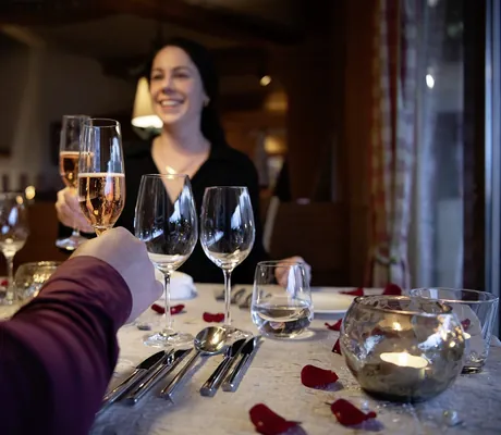 Paar an Restauranttisch im Salzano mit Rosenblättern prostet sich mit Sekt zu