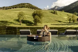 junge Frau beißt in Beere beim Floating-Frühstück im Pool des Terentnerhof