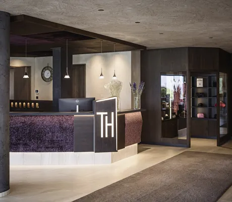 Lobby im Terentnerhof mit grauen Säulen und auberginefarbenem Tresen