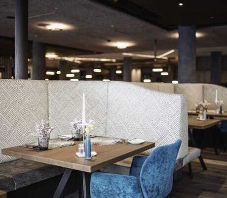Nische im Restaurant des Terentnerhof mit türkisfarbenem Sessel und grau-gemusterten Trennwänden