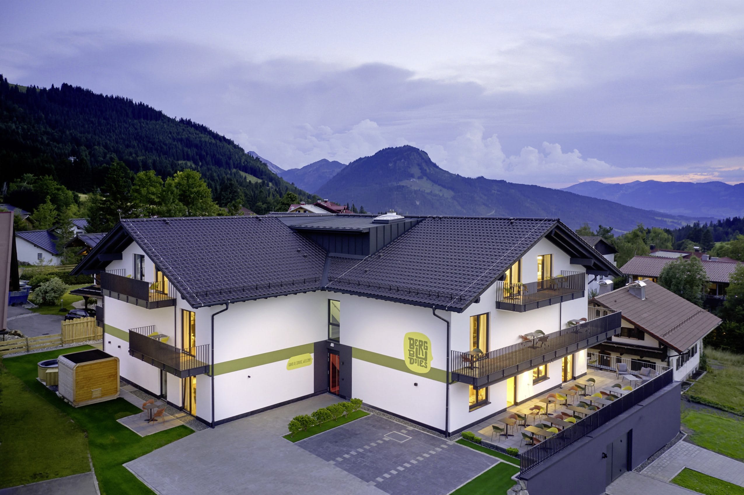 Blick aus der Vogelperspektive auf das BergBuddies-Hotel im Sommer, im Hintergrund die Berge