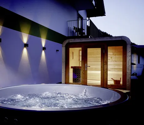 Spa-Area des BergBuddies-Hotel mit Außensaune und Hot Tube in der Dämmerung