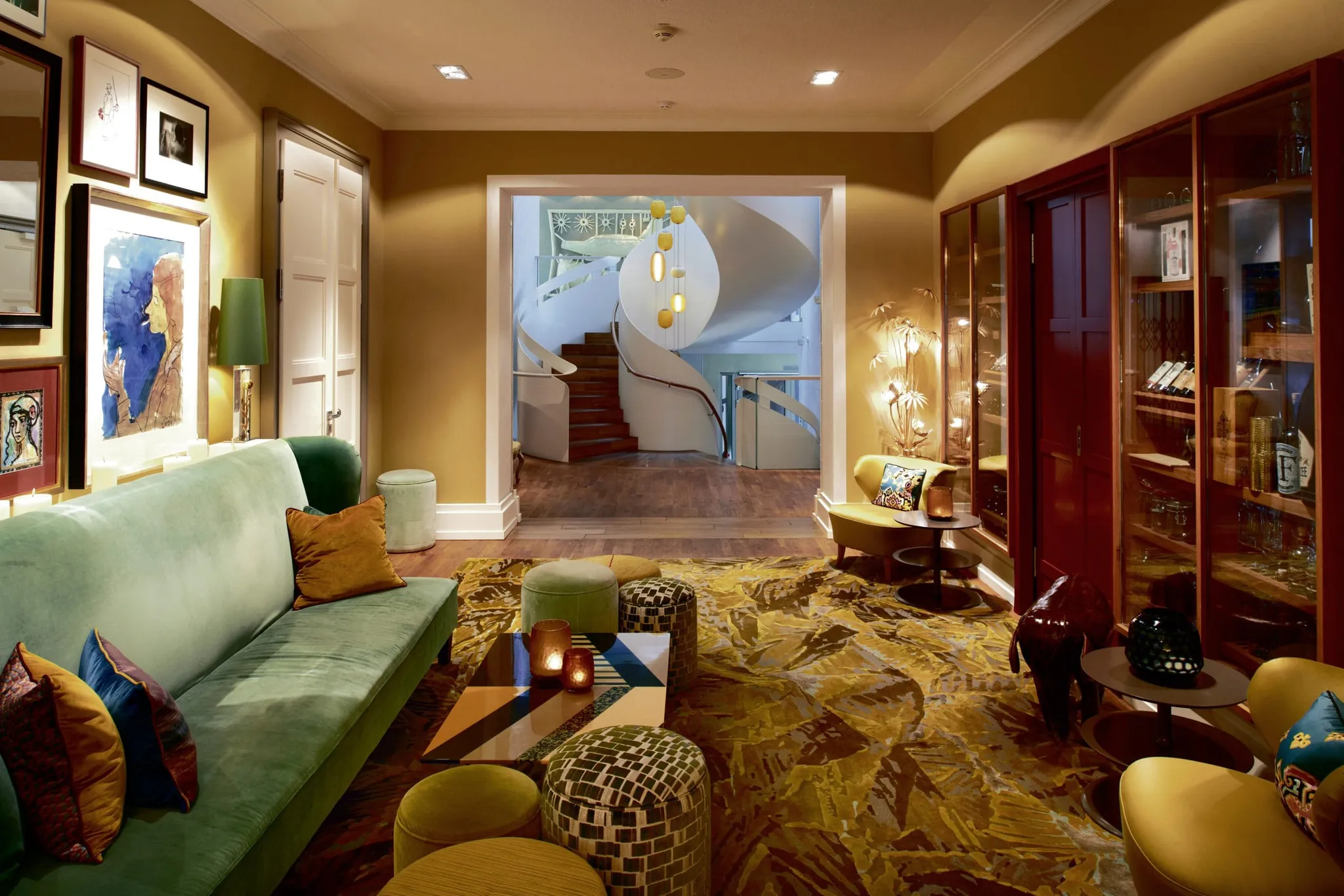 Lounge im LA MAISON mit grünem samtsofa und Blick auf den spiralförmigen Treppenaufgang