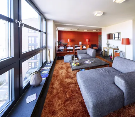 Ruhebereich des Day Spa im Altes Stahlwerk mit grauen Polsterliegen und rostrotem Teppich