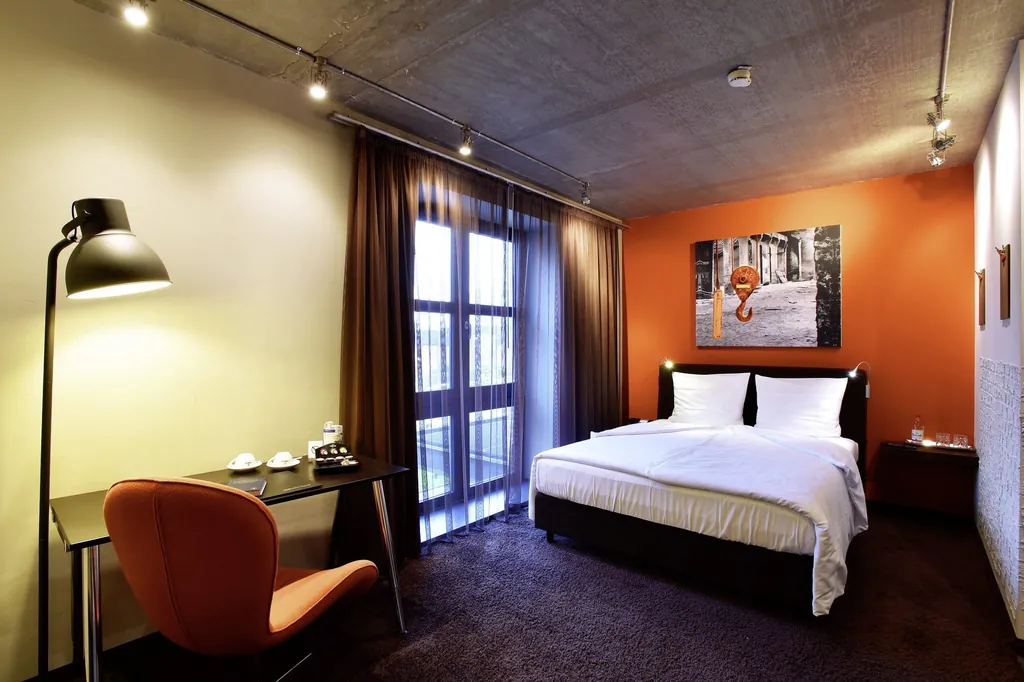 Zimmer im Altes Stahlwerk mit oranger Wand und Schreibtisch mit orangem Sessel