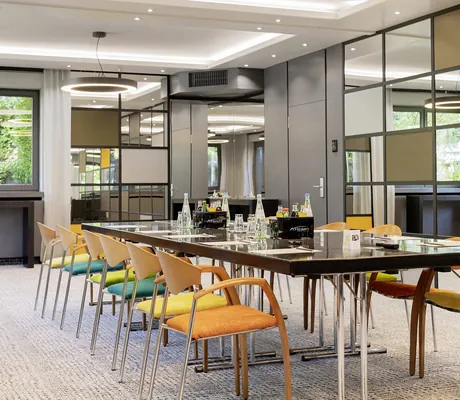 Konferenzraum im Atrium Hotel Mainz mit Spiegelwand und langem Tisch mit gelben und grünen Kissen