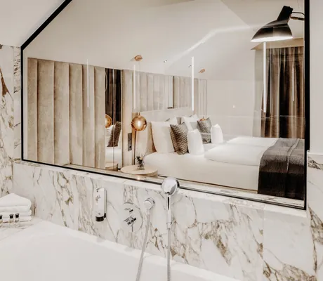 Blick vom Badezimmerspiegel im Marmorbad des Der Eisvogel aus auf das Doppelbett