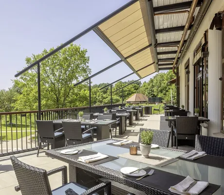 Restaurantterrasse im Flair Park-Hotel Ilshofen mit schwarzen Korbmöbeln und Blick in den Park
