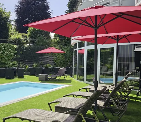 Outdoorpool mit roten Sonnenschirmen in Göbel's Landhotel