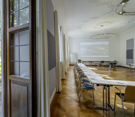 hohe Holztüre vom Tagungsraum im Kloster Seeon zum Garten mit Sitzbänken und Flipchart