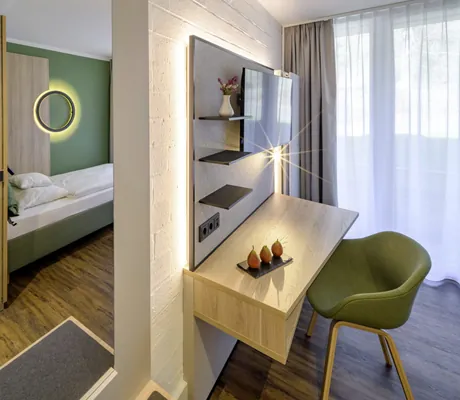 Einzelzimmer im Westerham - die Akademie mit grünem Bett und Schreibtischbereich mit grünem Stuhl