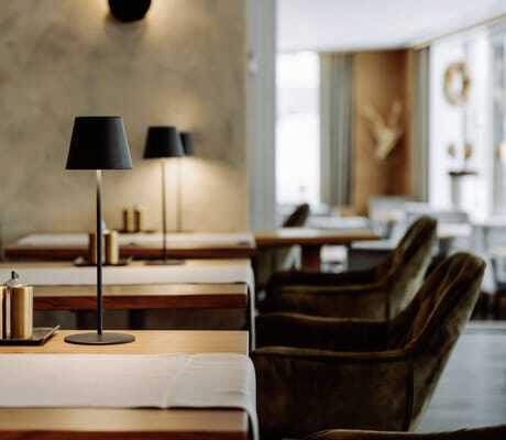 Tische mit schwarzen Tischlampen und grauen Läufern im Restaurant des Bodenmaiser Hof