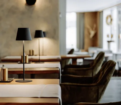Tische mit schwarzen Tischlampen und grauen Läufern im Restaurant des Bodenmaiser Hof