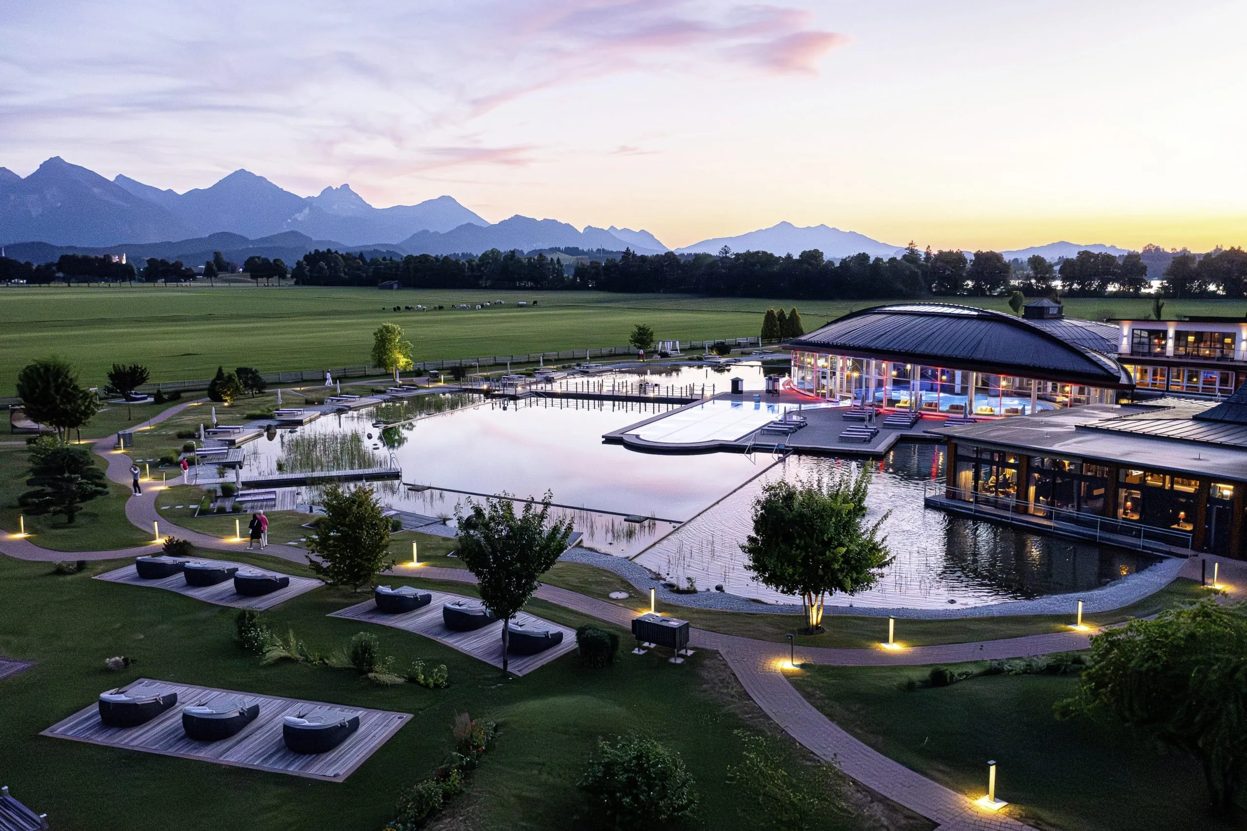 Blick von oben auf den riesigen Wellnessgarten des Wellnesshotels Das König Ludwig in Schwangau, im Hintergrund die Alpen