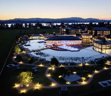 Luftaufnahme von der beleuchteten Wellnesslandschaft des Das König Ludwig Inspiration SPA in der Dämmerung