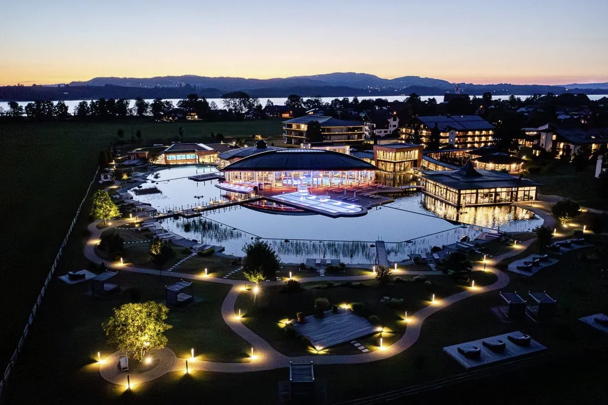 Luftaufnahme von der beleuchteten Wellnesslandschaft des Das König Ludwig Inspiration SPA in der Dämmerung