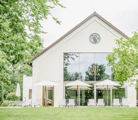 Fassade des Der Eisvogel mit Sonnenterrasse und weißen Sonnenschirmen und Eisvogel-Fenster