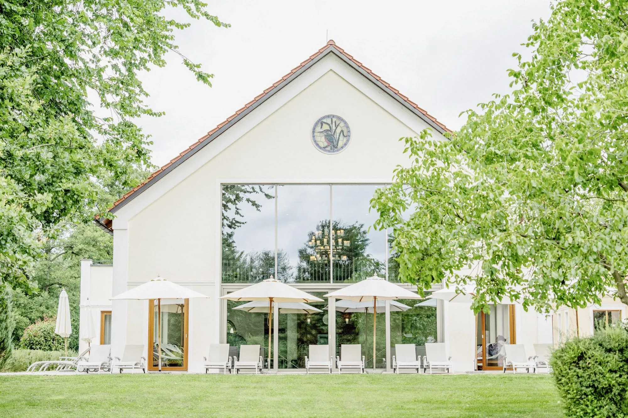 Fassade des Der Eisvogel mit Sonnenterrasse und weißen Sonnenschirmen und Eisvogel-Fenster