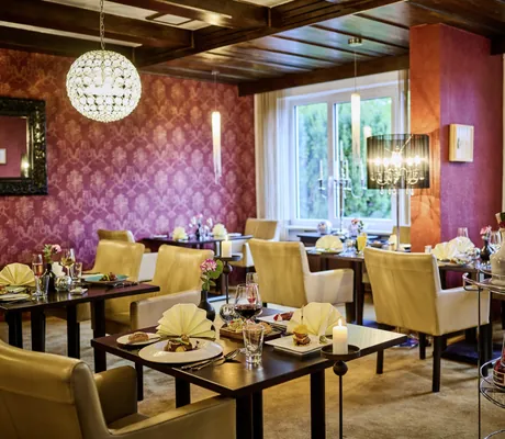 Fine Dining-Restaurant mit weinroter Tapete in Die Wutzschleife mit eingedeckten Tischen und Spirituosenwagen