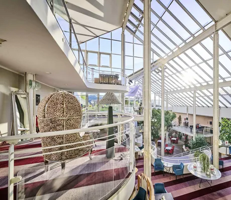 mehrstöckige Hotelhalle mit Glasdach in Die Wutzschleife mit Leopardensessel auf der Empore