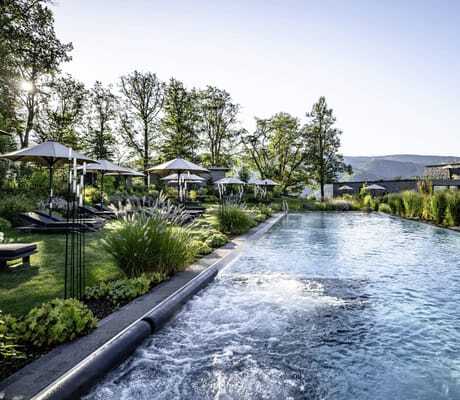 Outdoorpool mit weißen Sonnenschirmen im Naturgarten des Luisenhöhe Gesundheitsresort