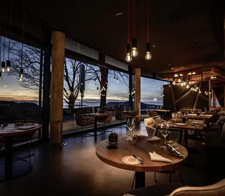 dunkel beleuchtetes Restaurant im Luisenhöhe Gesundheitsresort mit eingedeckten Tischen ohne Tischdecke